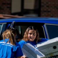 Three Alumni unloading a student's car.